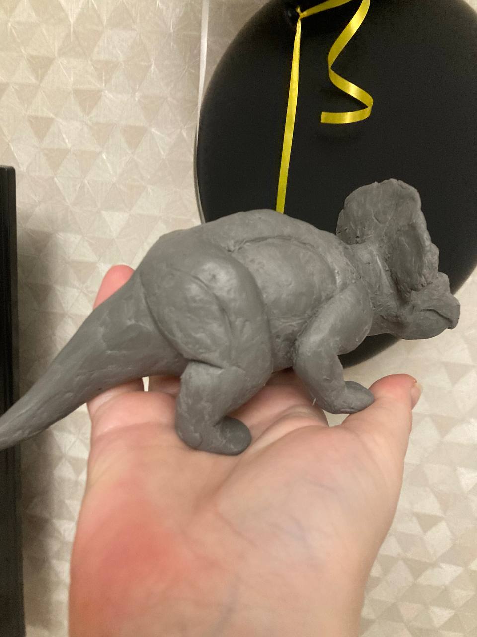 Small handmade triceratops sculpture held in one hand