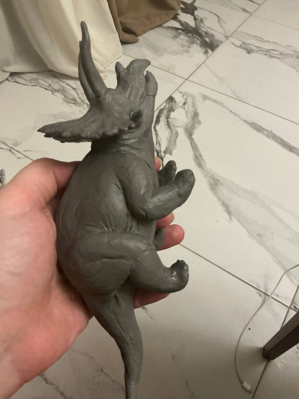 Small triceratops clay sculpture held in one hand