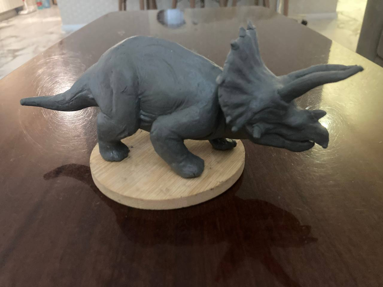 Handmade triceratops sculpture displayed on a wooden base
